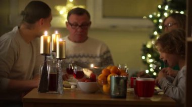 Yeni yıl kutlama. Masada, Noel ağacı ışıkları, mumlar masada, büyük aile yetişkin kırmızı şarap içmek.