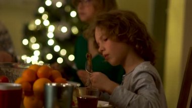 Genç oğlan bir tavuk budu yiyor ve onun kol mendil. Aile Noel yemeği. Ağ görgü kuralları, masada davranış kuralları