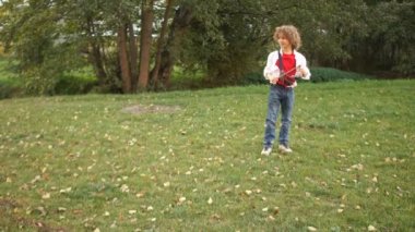 Neşeli bir çocuk çalışır ve yeşil çimenlerin üzerinde köpeğiyle oynuyor. Siyah ve beyaz köpek