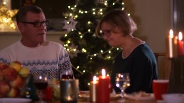 Olgun erkek ve kadın Noel ağacı ışıkları çerçevede mumlarıyla bir masada söz. İlk Tarih, yaşlı çift