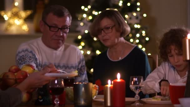 Die befreundete Familie feiert Weihnachten am Tisch. Opa legt einen Salat auf. Familie der Vegetarier, gesunde Lebensweise