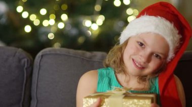 Mutlu çocuk Noel hediye kutusu açılıyor. Komik bebek yatak odasında Santa Claus şapka giymiş. Evde çocuk gülümseyen portresi. Xmas tatil kavramı