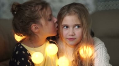 İki küçük kız arkadaşım sırlarını paylaşır. Her iki gülüyor Lay, onun kız kardeş kulağına fısıldayarak kız Noel akşam, yeni yıl çelenk