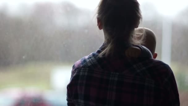 ウィンドウの前に立っている彼女の赤ん坊を保持する孤独な若い女性。母の日 — ストック動画