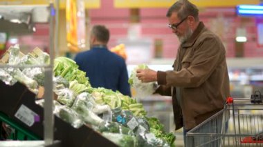 Emekli bir süpermarkette alışveriş. Bir adam bir vejetaryen salata sebze alır ve onları bir arabaya koyar