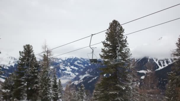 Лыжный подъемник на фоне заснеженных гор. Пустые стулья движутся на фоне красивого горного зимнего пейзажа — стоковое видео
