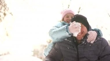 Bir kız babası ile kartopu oynuyor, yüzünü kar ile smear neşeyle gülüyorlar. Mutlu kış aile tatilleri