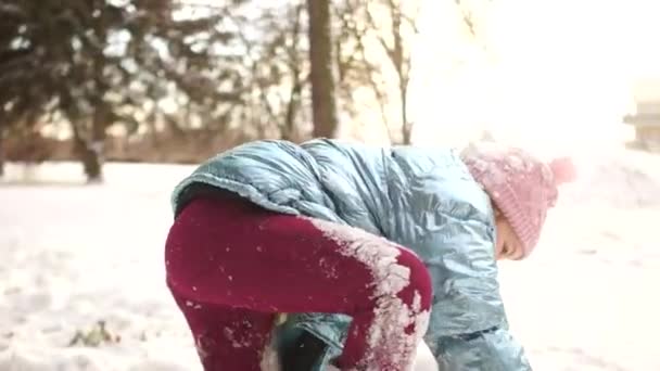 微笑んでいる女の子が公園で冷たい晴れた朝を楽しんでいます。陽気なアクティブな女子高生、冬の時にカメラを持つ楽しみ屋外で雪玉を投げる — ストック動画