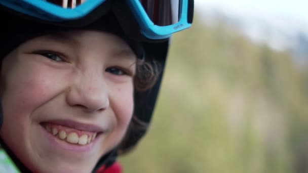 Teen boy in casco e occhiali si siede in una cabina di risalita. Il bambino ride felicemente. Vacanze divertenti in montagna, stile di vita attivo — Video Stock