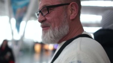 Airport çevresinde uzanmanız üst düzey turist gri sakallı adam portresi. Gezgin gözlük ve beyaz kazak giyer