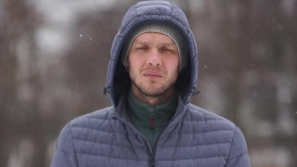 Portret van een jonge knappe man in een capuchon op de achtergrond van de winter koud bos — Stockvideo