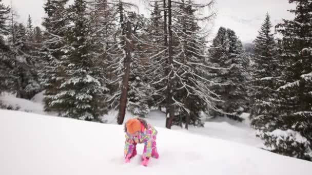 Gelukkig peuter meisje in warme vacht en gebreide muts gooien van sneeuw en een plezier in het winter forest, outdoor portret — Stockvideo