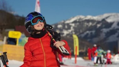 Çocuğa bir kayak merkezi. Bir çocuk için Kayak, tam ekipmanlı, kırmızı bir ceket, gözlük ve kask gökyüzüne görünüyor. Parlak güneş parlıyor