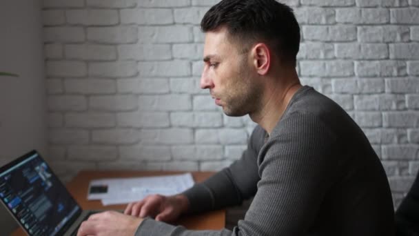 Portrait rapproché d'un jeune homme travaillant avec un ordinateur portable dans le bureau. Indépendante au travail — Video