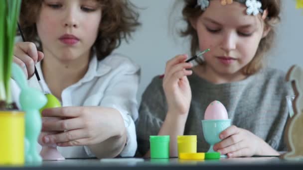 Los colegiales divertidos adornan los huevos de Pascua con borlas. Chica sosteniendo un huevo rosa. Feliz Pascua familiar — Vídeos de Stock