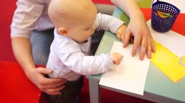 Bir yıl eski bebek ilk kez babası yanında mum boya kalemi çizmeye öğrenir. Çocuk gelişimi. Yukarıdan görüntülemek.