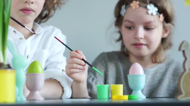 Portrait rapproché d'un garçon et d'une fille bouclés décorer des œufs de Pâques. Décor de Pâques de printemps, master class — Video