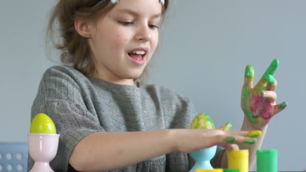 Frohe Ostern. Das Mädchen zeichnet mit den Fingern, bemalt Ostereier. Gelbe verschmutzte Hände — Stockvideo