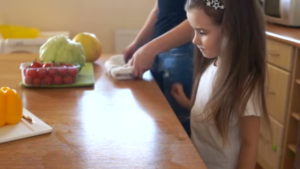 Hermosa chica se está preparando para hacer una ensalada en la cocina con su madre. Madre e hija en la cocina. Chica se mueve tabla de cortar con pimientos dulces multicolores — Vídeo de stock