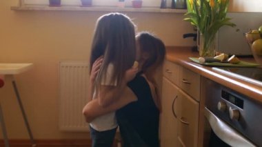 Uzun saçlı kız annesi mutfakta koştu. Bir kadın kızı hugs ve onu öper. Mutlu ev kadını