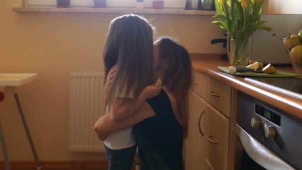 Long-haired girl ran to her mother in the kitchen. A woman hugs her daughter and kisses her. Happy housewife — Stock Video