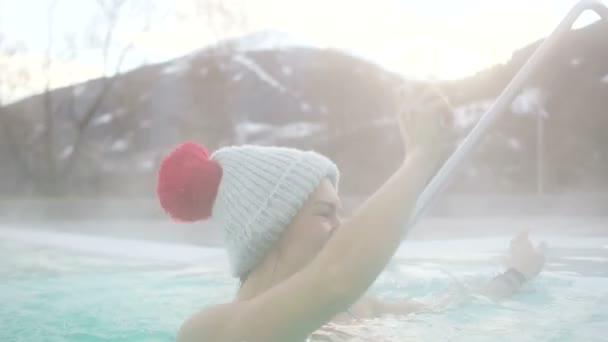 Счастливая молодая женщина весело плавает в горячей термальной весной в горах зимой — стоковое видео