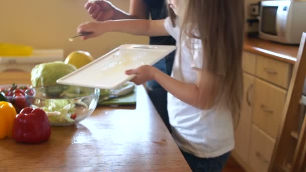 Mother and daughter try a leaf of lettuce. The girls cook dinner together. Moms helper, family dinner — Stock Video
