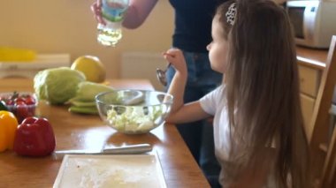 Küçük kız ve annesi salata hazırlayın, bitkisel yağ ile doldurun. Vejetaryen diyet, sağlıklı gıda aile içinde