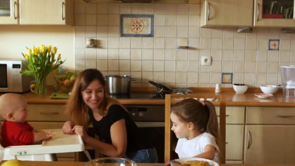 Έξυπνη μάνα με δυό παιδιά στην κουζίνα. Μια γυναίκα τροφοδοτεί δύο παιδιά. Ημέρα της μητέρας — Αρχείο Βίντεο