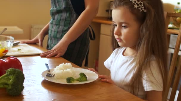 Маленька брюнетка дошкільного відмовляються їсти здорову їжу. Мама штовхає її плита — стокове відео