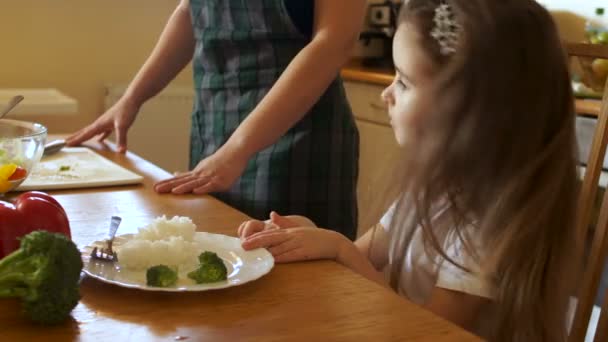 La piccola bruna prescolastica rifiuta di mangiare cibo sano. Mamma spinge il suo piatto — Video Stock