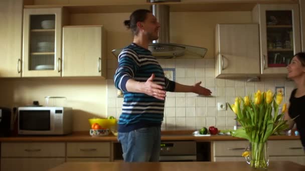 Хлопець і дівчина обманюють на кухні. Жінка хоче стрибати на чоловіка, він відступає, почуття гумору, дурень — стокове відео