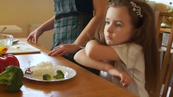 Дівчина на кухні не хоче їсти рис і брокколі. Сумний поклав голову на руки — стокове відео