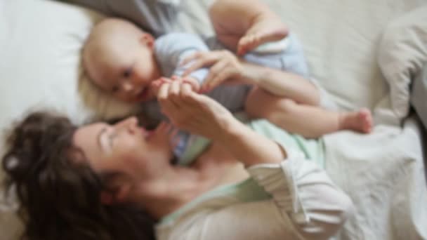 Bebê feliz e mãe na cama olham um para o outro. Bom dia de família, dia de mães — Vídeo de Stock