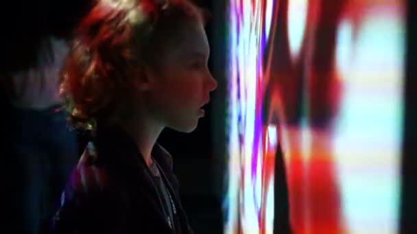 Curly écolier regarde le mur interactif avec des motifs abstraits. Le garçon est surpris et fasciné. Les enfants et la technologie du futur 