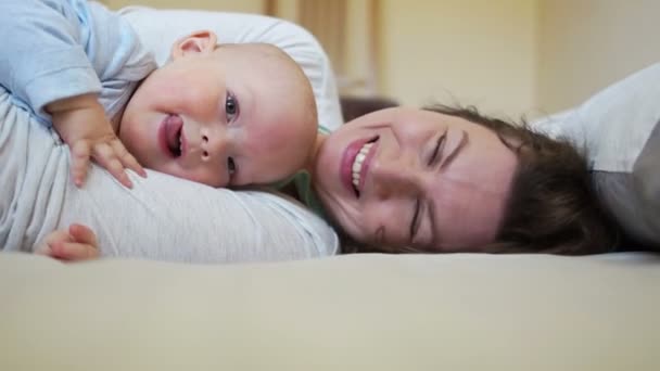 Umarmungen und Küsse von Mutter und Baby am Morgen im Bett. Muttertag — Stockvideo