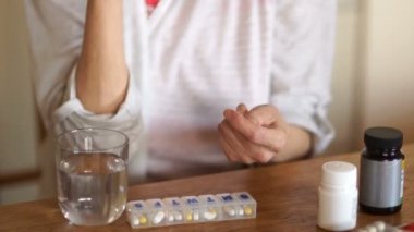 Artrit muzdarip bir kişi yakın çekim kol. Olgun kadın hapları ve su ile vitamin alır. Tıp ve eczacılık kavramı