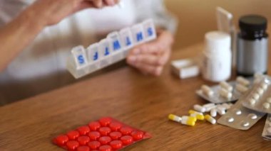 Bir yaşlı kadın, tabletler için bir kapsayıcı bir plastik Organizer'da haplarını katlama elleri. Eczane konsepti. Artrit Hastalar eller