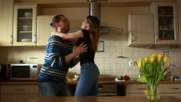 Adorável casal apaixonado brincando em sua casa na cozinha. Homem e mulher riem e lutem — Vídeo de Stock