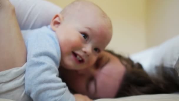 Nauwe portret van een baby in de armen van zijn moeder in de slaapkamer in de ochtend bed — Stockvideo