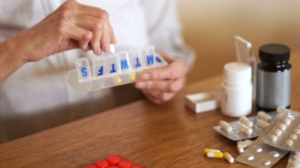 Una mujer pone sus pastillas en un recipiente de plástico. Pensionista toma una dosis diaria de píldoras y vitaminas — Vídeos de Stock