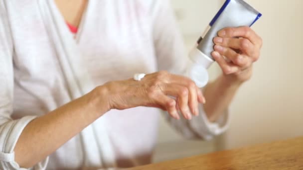 Mujer anciana aplicando crema de loción hidratante en la palma de la mano, aliviando dolores. Anciana mayor que experimenta severos dolores reumáticos artritis, masaje, calentamiento del brazo. Cerrar, copiar espacio, fondo — Vídeo de stock