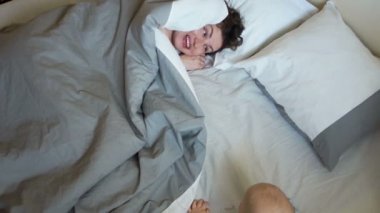 Anne ve bebek saklambaç oynayalım sabahları yatakta. Annesi bir battaniye ile onun baş ile kaplıdır, çocuk ona tarar ve açılır