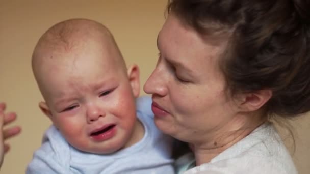 Ein einjähriges Baby weint in den Armen seiner Mutter. Porträt schließen, Muttertag — Stockvideo