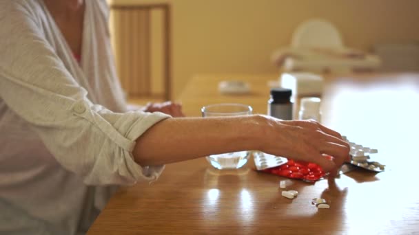 Arthritische Gelenke. Frau nimmt Tabletten und trinkt sie mit Wasser, während sie am Tisch sitzt