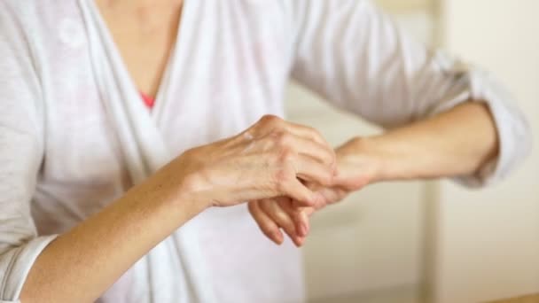 Close-up de uma mulher idosa com artrite esfrega as mãos com pomada de cura. Conceito de medicina e farmacologia — Vídeo de Stock