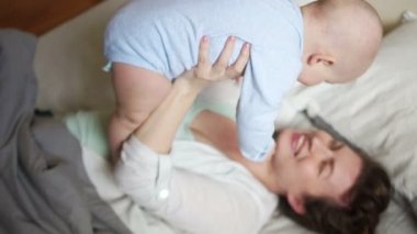 Genç kadın ve bebeğinin sabahları yatakta iyi eğlenceler. Mutlu aile, anneler günü