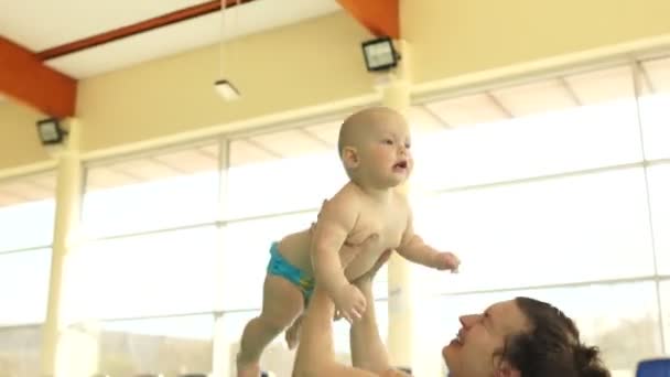 Счастливая мама бросает ребенка в бассейн. Развитие детей, День матери — стоковое видео