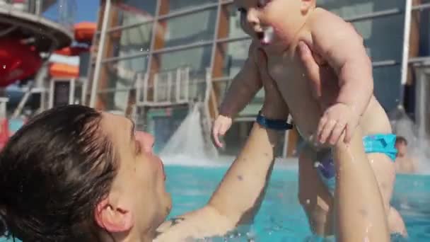 Vrolijk baby en vader have fun in het waterpark. Een man roept een kind van boven het water — Stockvideo