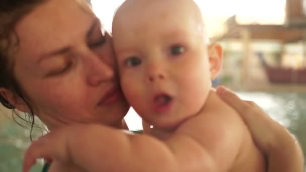 Retrato de la madre feliz y su bebé en la piscina cubierta. El desarrollo de los niños, el día de las madres. Salpicaduras de primer plano — Vídeos de Stock